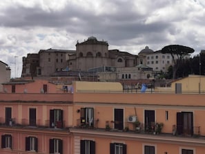 A historic building with multiple levels and a dome, surrounded by residential buildings with balconies and potted plants. - Mocenigo Vatican Suites (Rome)