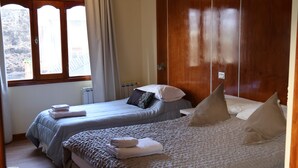 A bedroom with two beds, wooden wardrobe, and a window with curtains. - Valle Frio Ushuaia (Ushuaia)