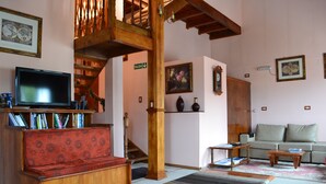 A living room with a wooden staircase, a sofa, a coffee table, and a television. - Valle Frio Ushuaia (Ushuaia)