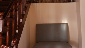 A staircase with a wooden handrail leading to a landing with a chair and a wall-mounted shelf with small figurines. - Valle Frio Ushuaia (Ushuaia)