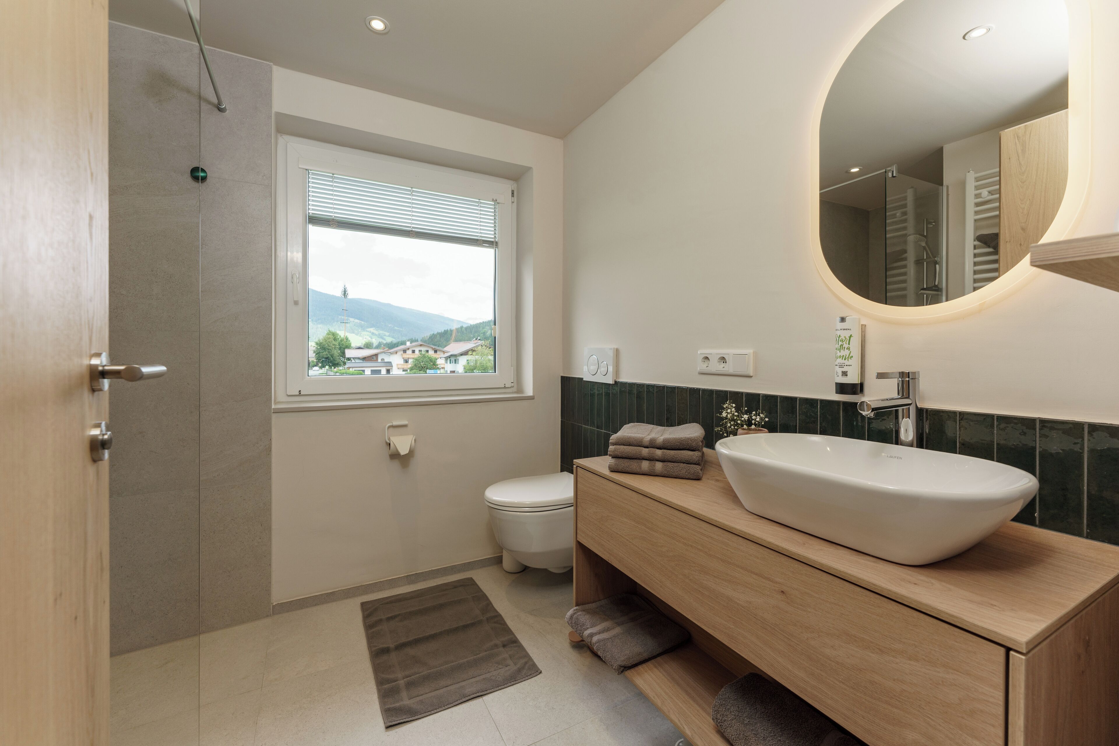 Een moderne badkamer met een grote wastafel, een spiegel en een raam met uitzicht.
