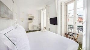 Habitación de hotel con cama, televisión, una mesita y ventana con vistas a edificios.