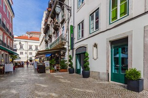 Egy macskaköves utca, melynek mindkét oldalán épületek sorakoznak, köztük egy zöld ajtós szálloda, melynek a tábláján a „hotel gel rosso” felirat olvasható.