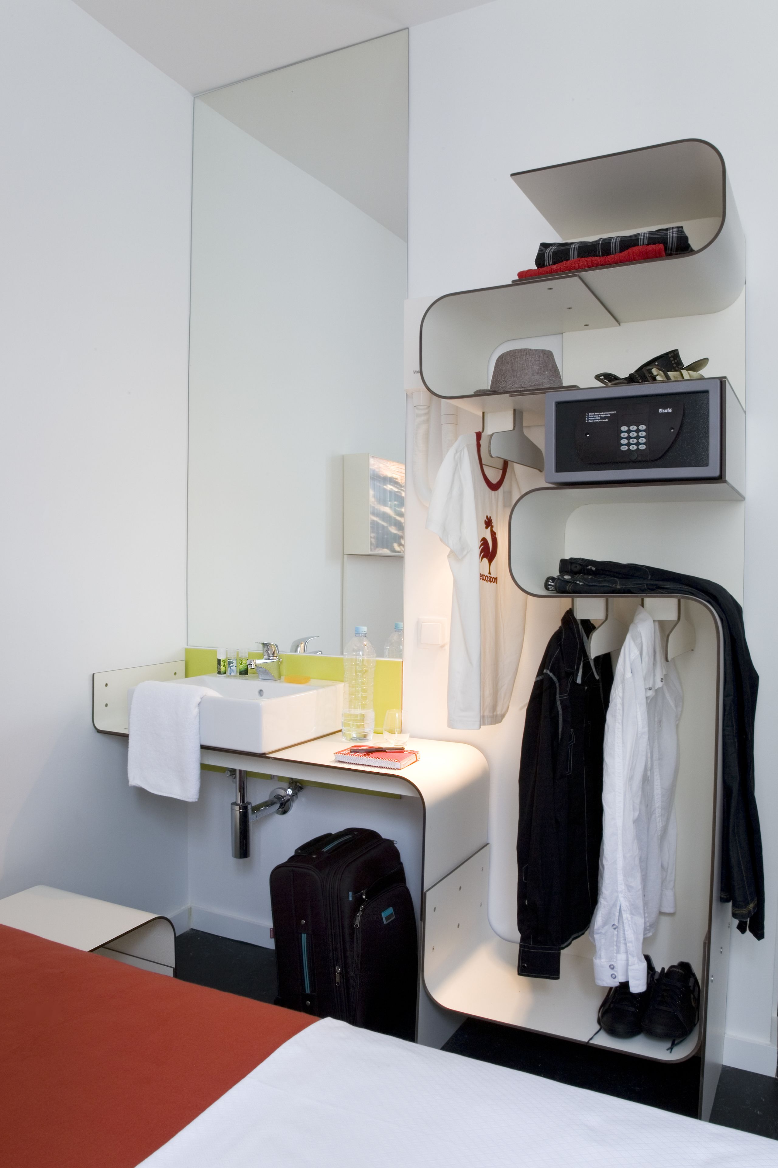 A hotel room with a bed, a desk, a mirror, a sink, and a microwave.