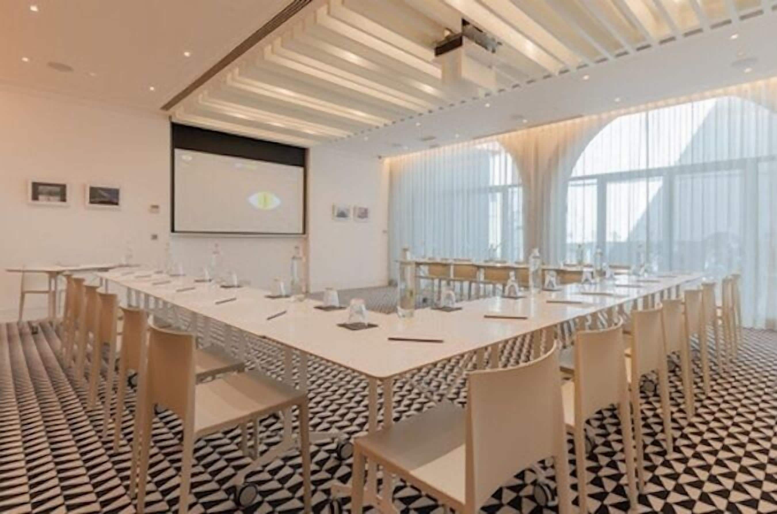 Une salle de conférence équipée d’une longue table, de chaises et d’un écran de projection.