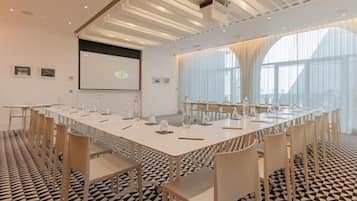 Une salle de conférence équipée d’une longue table, de chaises et d’un écran de projection.