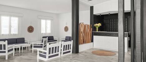 Un salon moderne comprenant un ensemble de canapés, des fauteuils, une table basse, une cheminée et un coin cuisine.