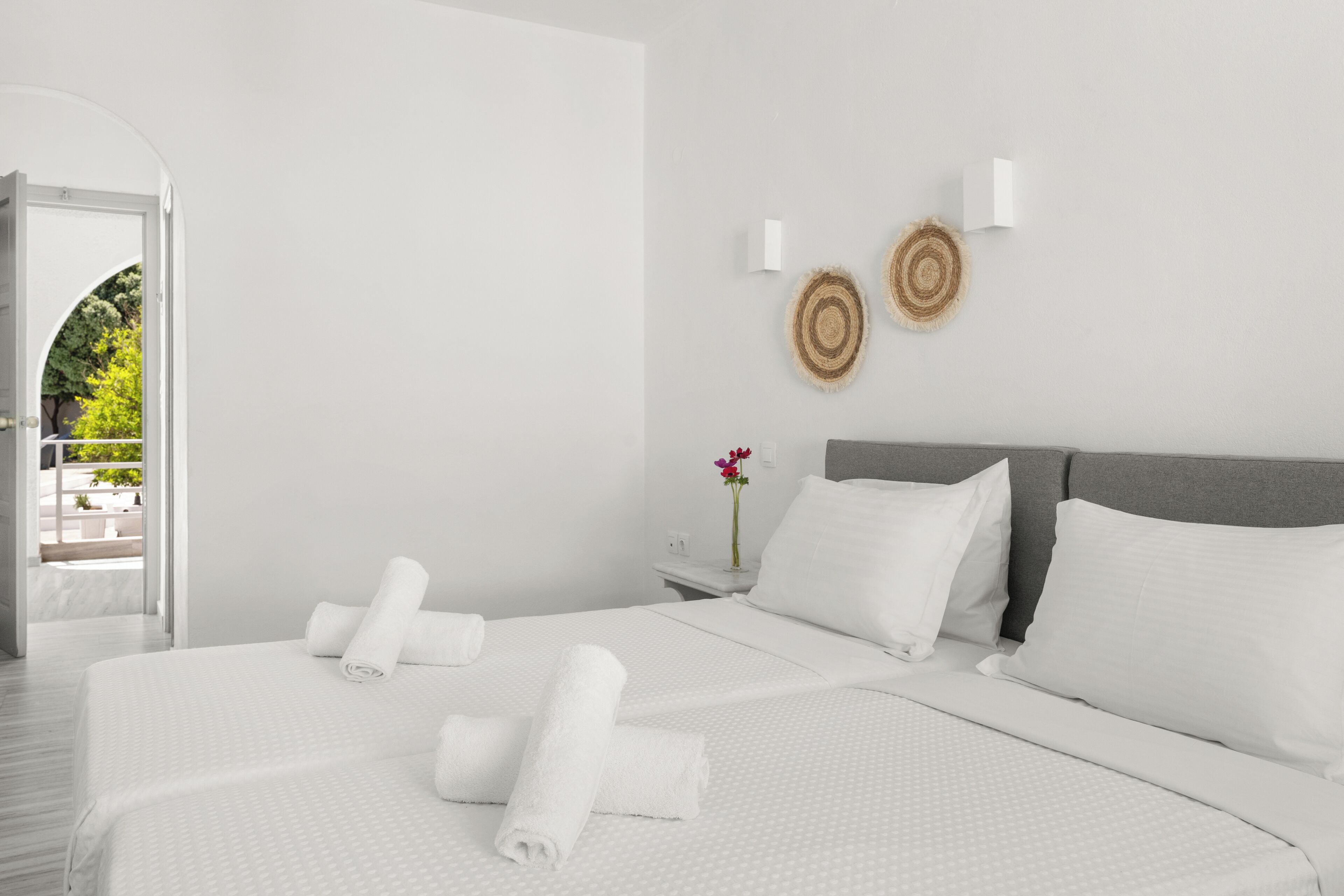 A modern hotel room with a large bed, a nightstand, and a view of a balcony.