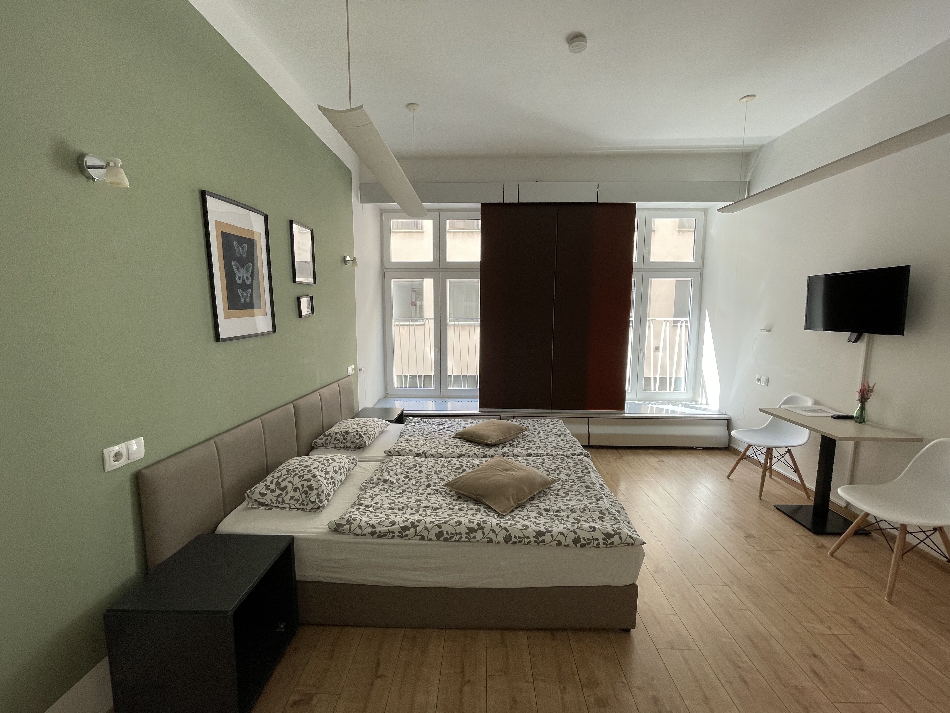 A modern bedroom with a bed, a desk, and a TV.