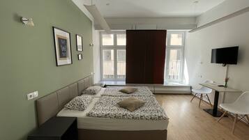 Ein modernes Schlafzimmer mit Bett, Schreibtisch und Fernseher.