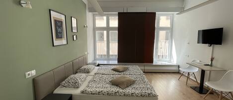 A modern bedroom with a bed, a desk, and a TV.