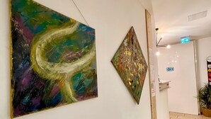 A hallway with two abstract paintings on the walls and a wooden floor. - Dan In'n Out (Vienna)