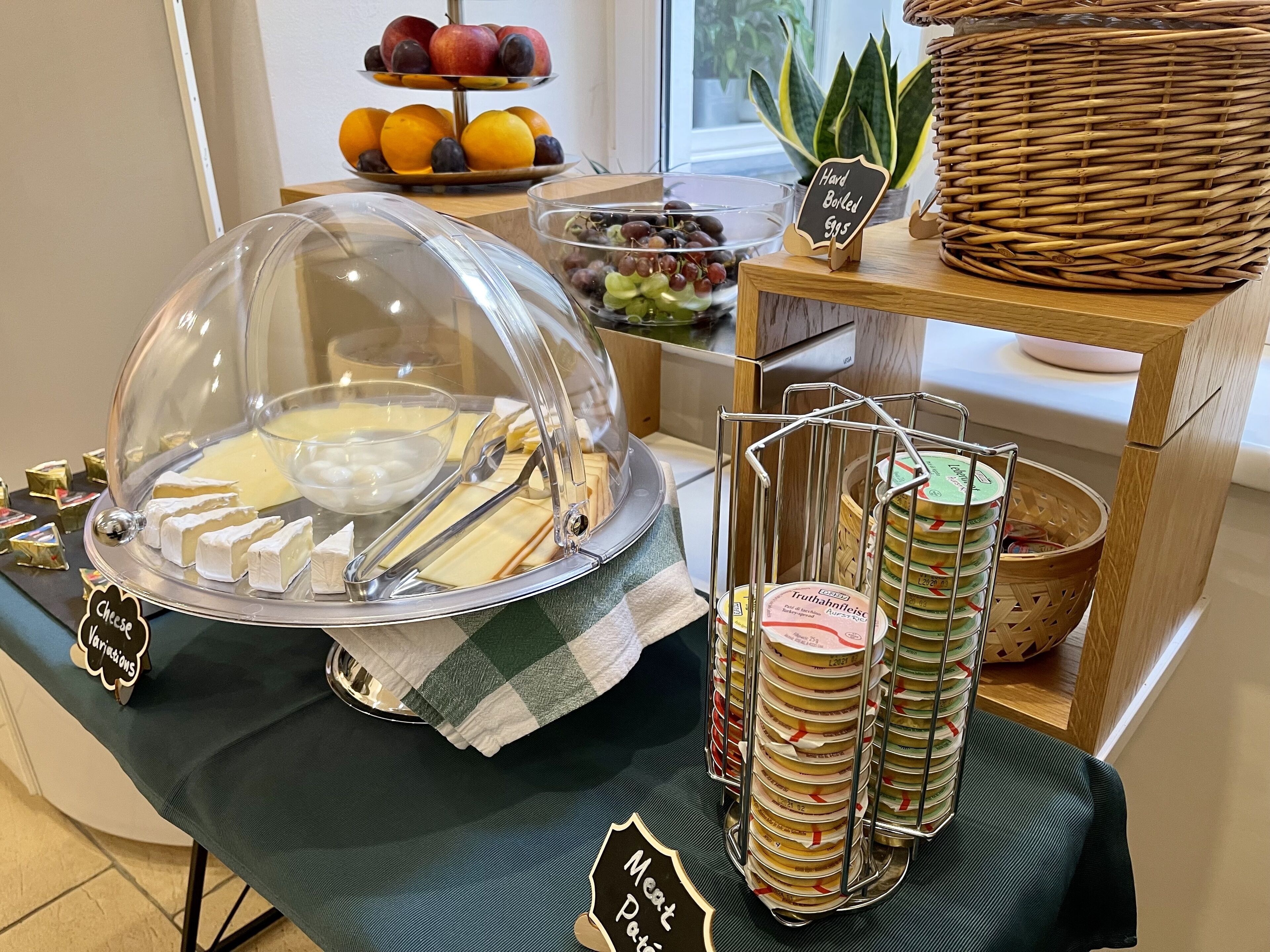 Una mesa de buffet con una presentación de quesos, una bandeja de frutas y una sección de carnes.