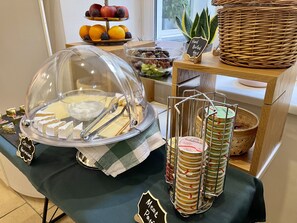 A buffet setup with a cheese display, a fruit tray, and a meat section.
