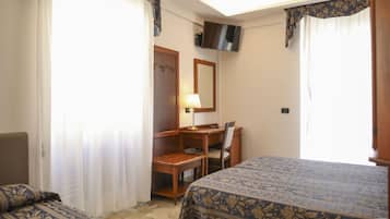 Camera d'albergo con due letti, una scrivania, una sedia, un televisore e una lampada.
