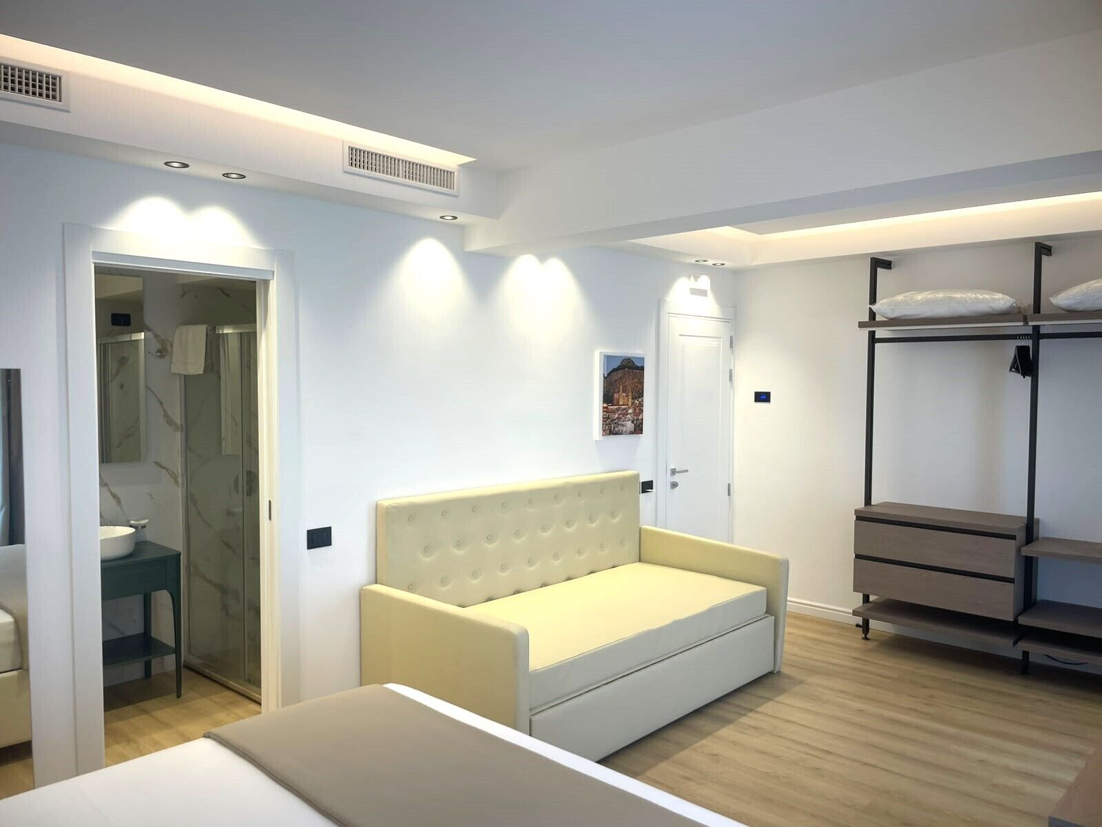 Un dormitorio moderno con cama, sofá, armario y baño.