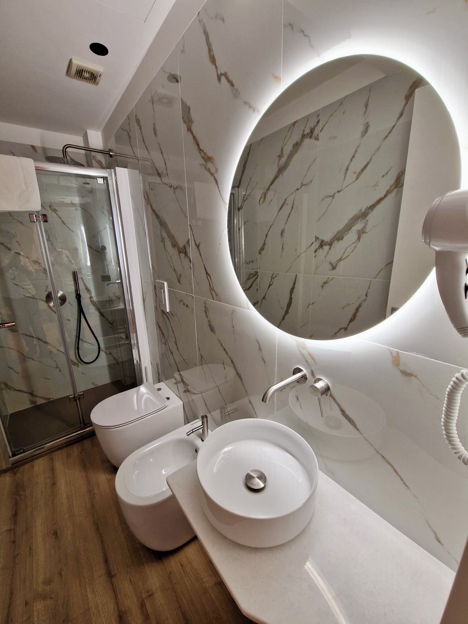 A modern bathroom with a glass shower enclosure, two sinks, and a large mirror.