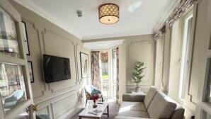 A living room with a patterned carpet, a sofa, a coffee table, and a television mounted on the wall. - Waterloo Townhouse & Suites (Dublin)
