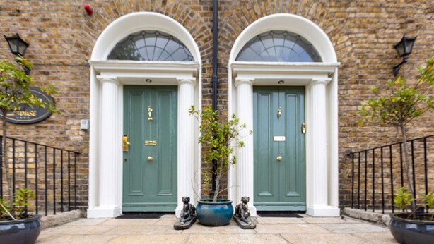A building facade with two green doors, a potted plant, and two statues. - Waterloo Townhouse & Suites (Dublin)