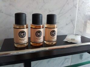 Three bottles of Country Club hair and body shampoo, one bottle of Country Club bath and shower gel, and a bar of Country Club soap on a black countertop with a marble backsplash. - StayInCologne (Cologne)