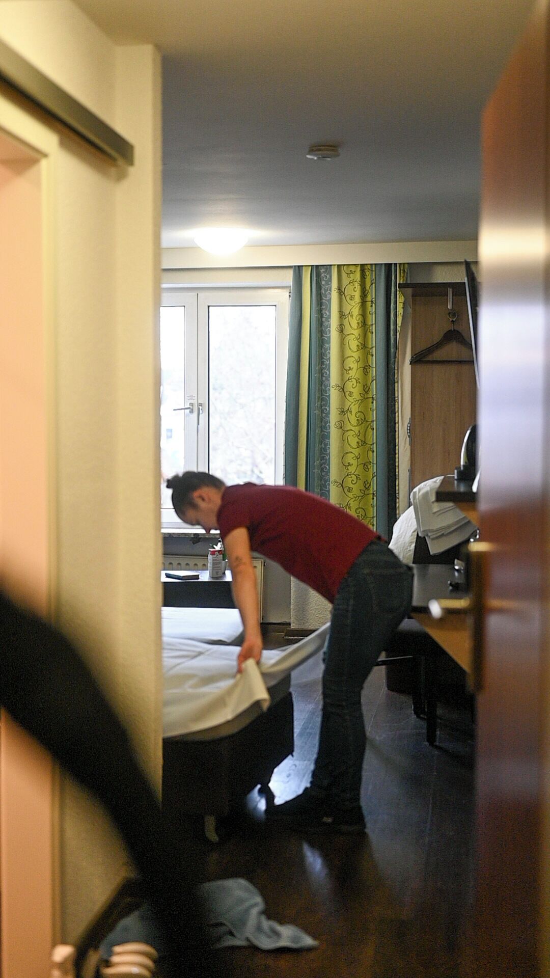 A room with a bed, a desk, a chair, and a window with curtains.
