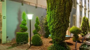 A hotel building with a sign reading "HOTEL BLAUER KARPFEN" and a well-maintained garden with trimmed bushes and a lamp post. - Hotel Blauer Karpfen (Oberschleissheim)