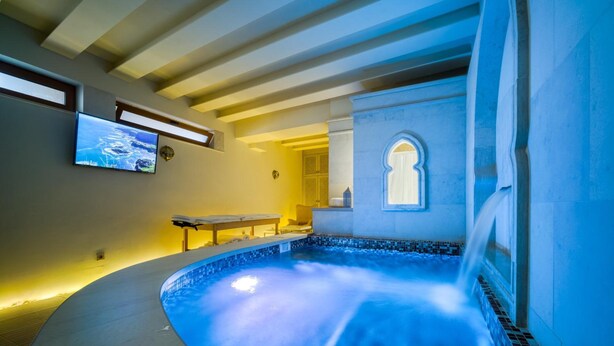 Ein Wellnessbereich mit Whirlpool, Fernseher und kleinem Tisch.