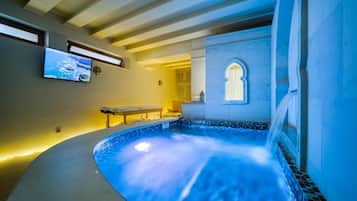 A spa area with a hot tub, a television, and a small table.