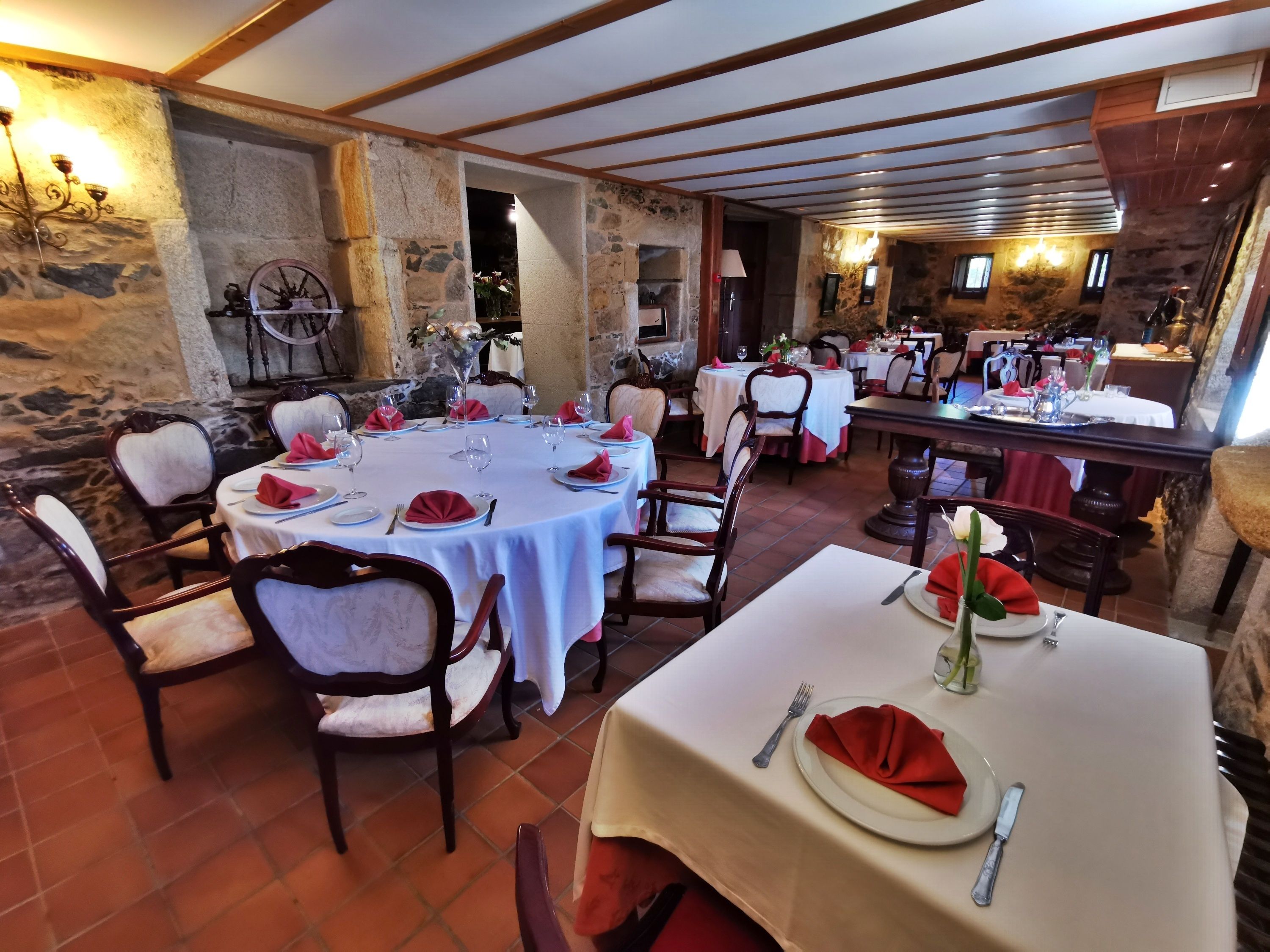 Ein Restaurant mit runden Tischen, Steinwänden und rustikalem Interieur.
