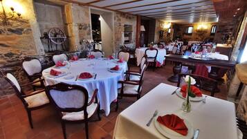 Ein Restaurant mit runden Tischen, Steinwänden und rustikalem Interieur.