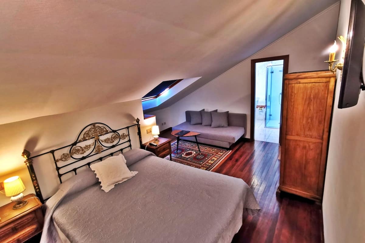 Un dormitorio con cama, sofá, mesita de noche y armario de madera.