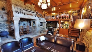 A rustic interior with a stone fireplace, leather seating, and a bar area. - Pazo do Souto (Carballo)