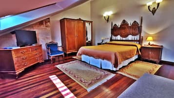 A bedroom with a bed, wooden wardrobe, television, and a desk.