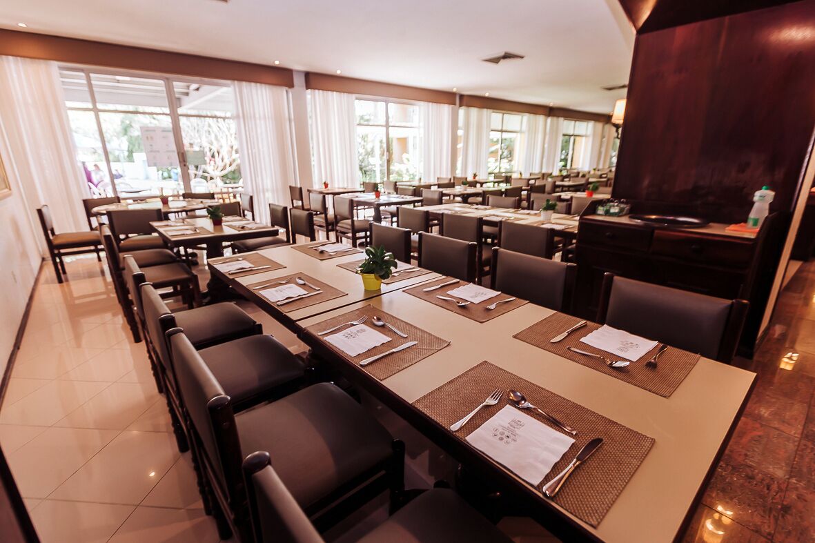 A conference room with multiple tables and chairs, large windows, and a modern interior design.