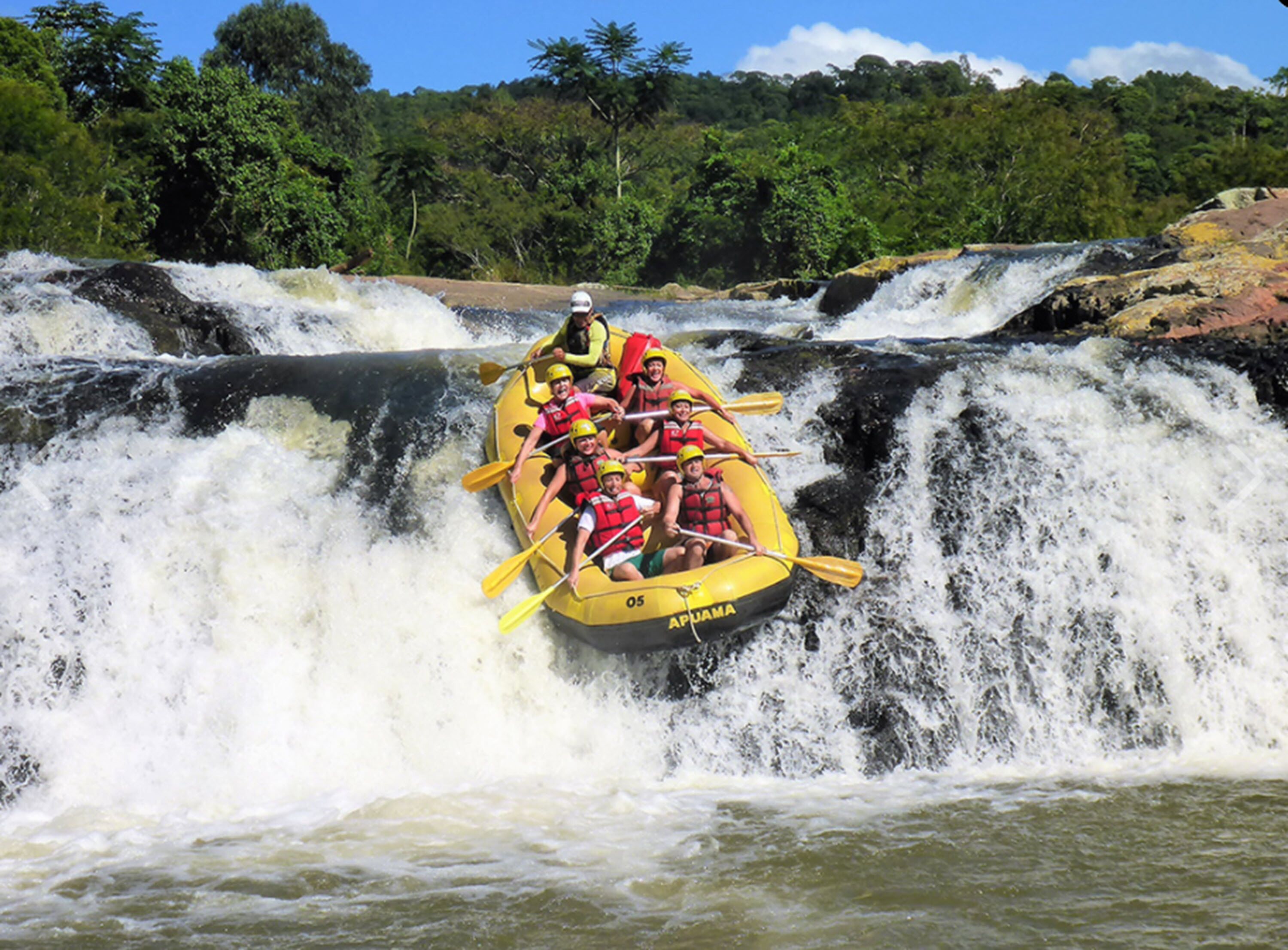Un grupo de personas en una balsa amarilla recorriendo una cascada.