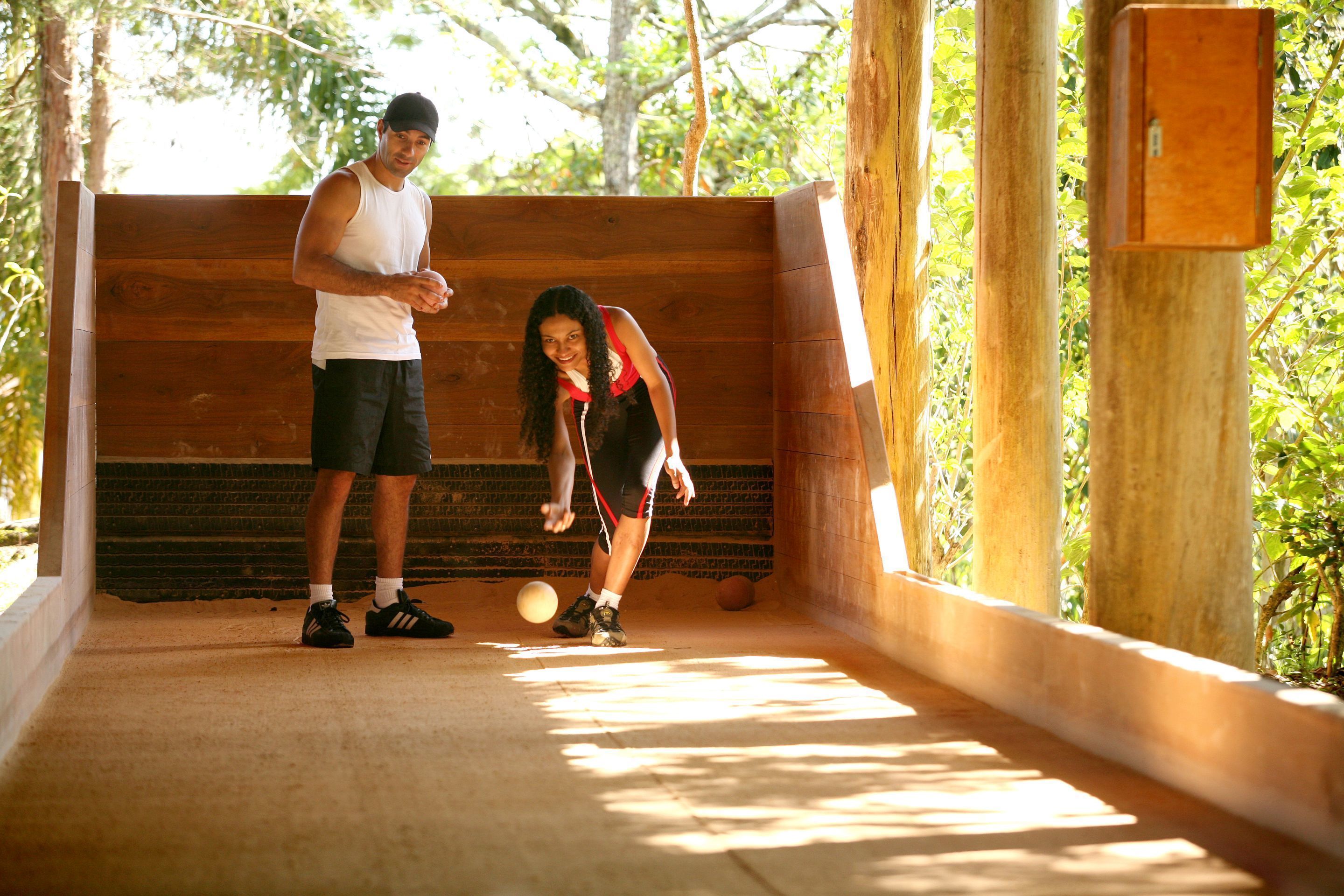 A man and a woman playing with a ball in an outdoor wooden structure with a brick wall.