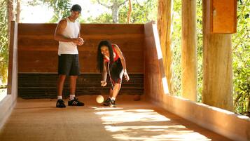 A man and a woman playing with a ball in an outdoor wooden structure with a brick wall.