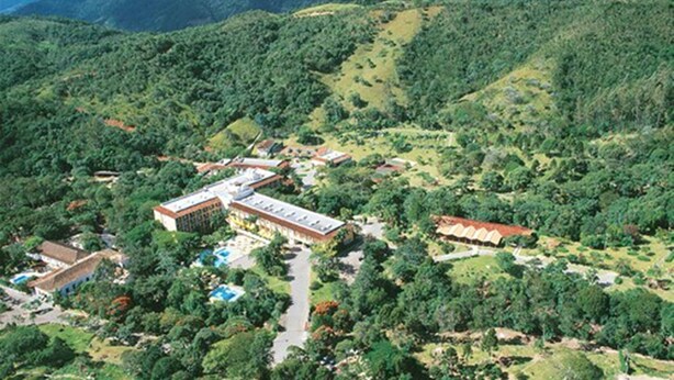An aerial view of a resort with multiple buildings, a swimming pool, and lush greenery.