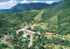 Una vista aerea di un resort con diversi edifici, una piscina e vegetazione lussureggiante.