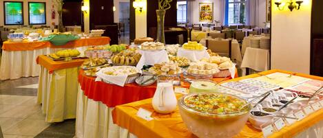 A buffet setup with various food items and a large bowl of salad.