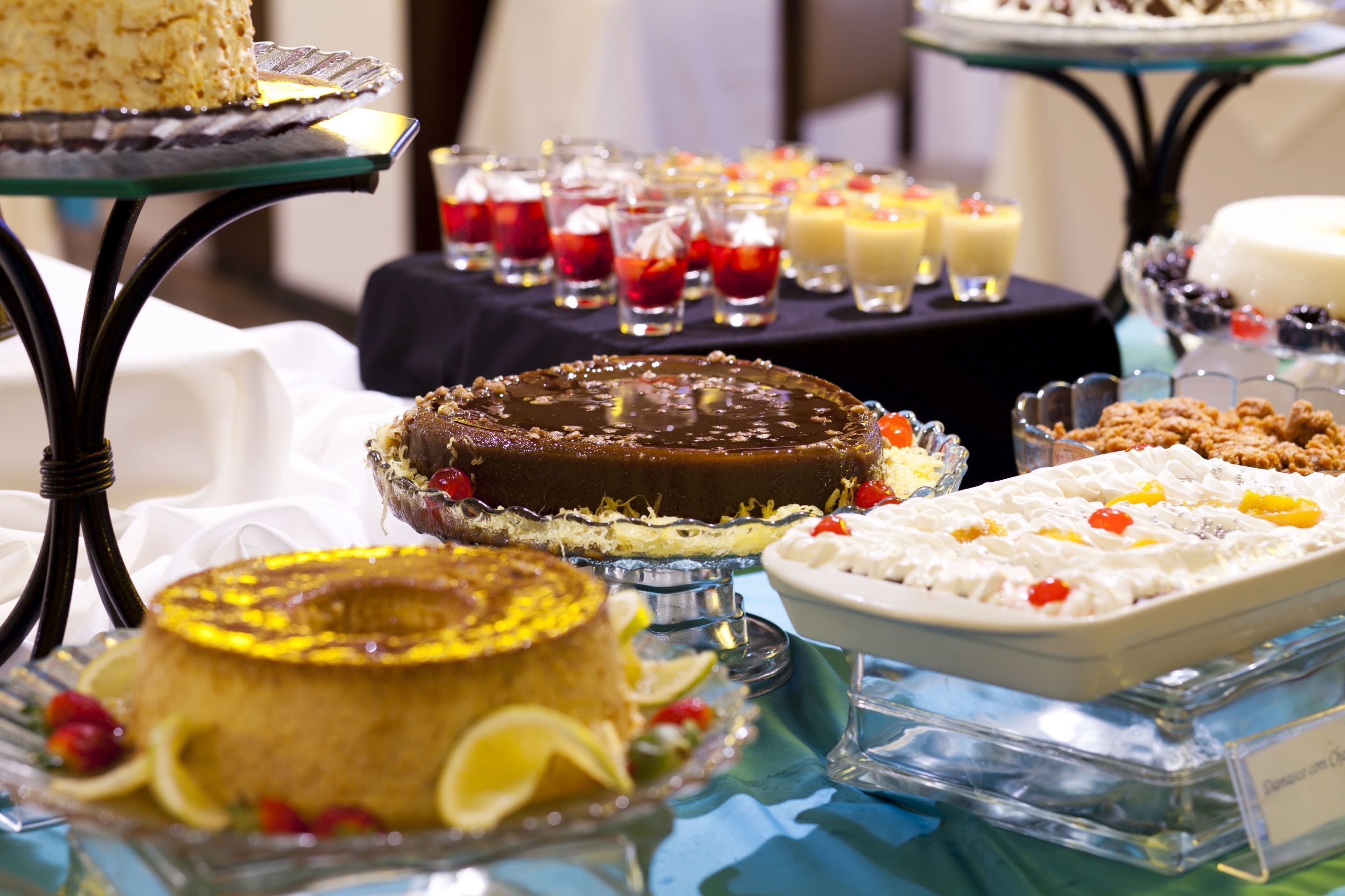 A variety of desserts on display, including cakes and pastries, arranged on glass stands and platters.