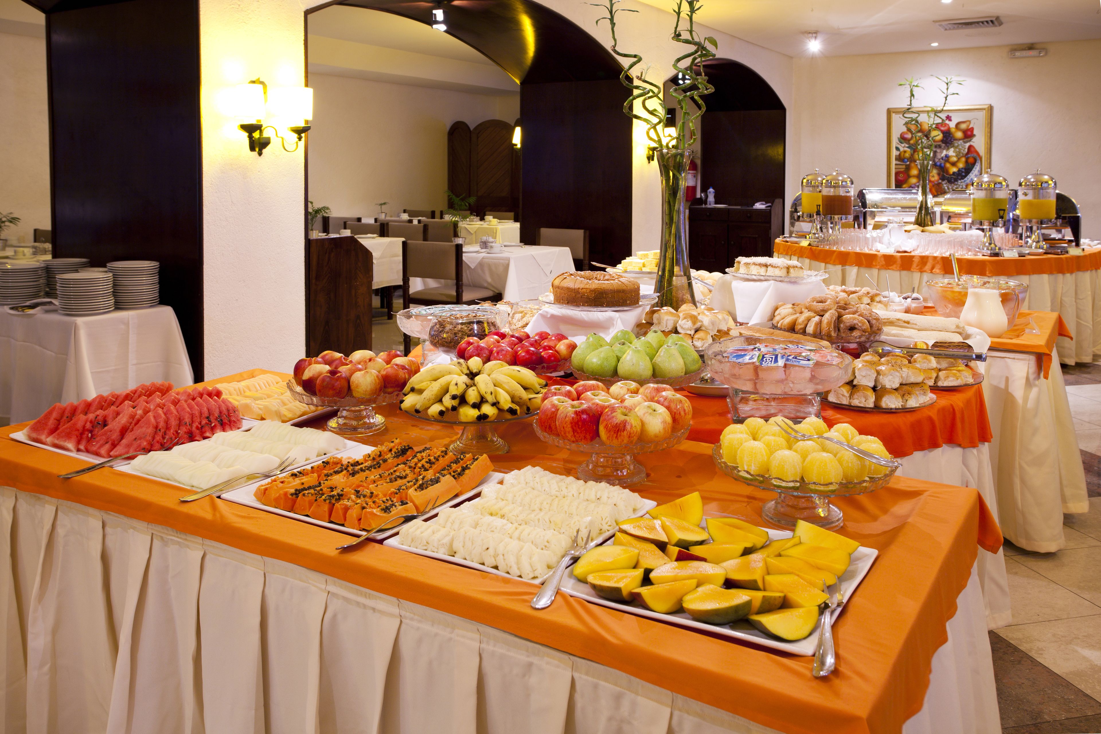 A buffet with various fruits, pastries, and a cake.