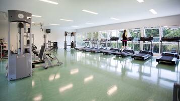A gym with treadmills, weight machines, and large windows.