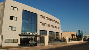 A modern hotel with a glass facade, multiple floors, and a parking sign. - Hotel Porcel Avant (Torrejón de Ardoz)