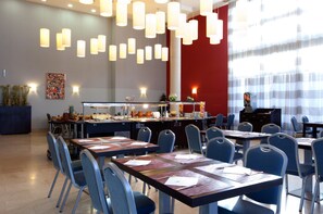 Enjoy communal dining in this stylish space with pendant lighting, a buffet counter, and a vibrant abstract art piece.