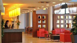 A modern lobby with a reception desk, red seating, and large windows. - Hotel Porcel Avant (Torrejón de Ardoz)