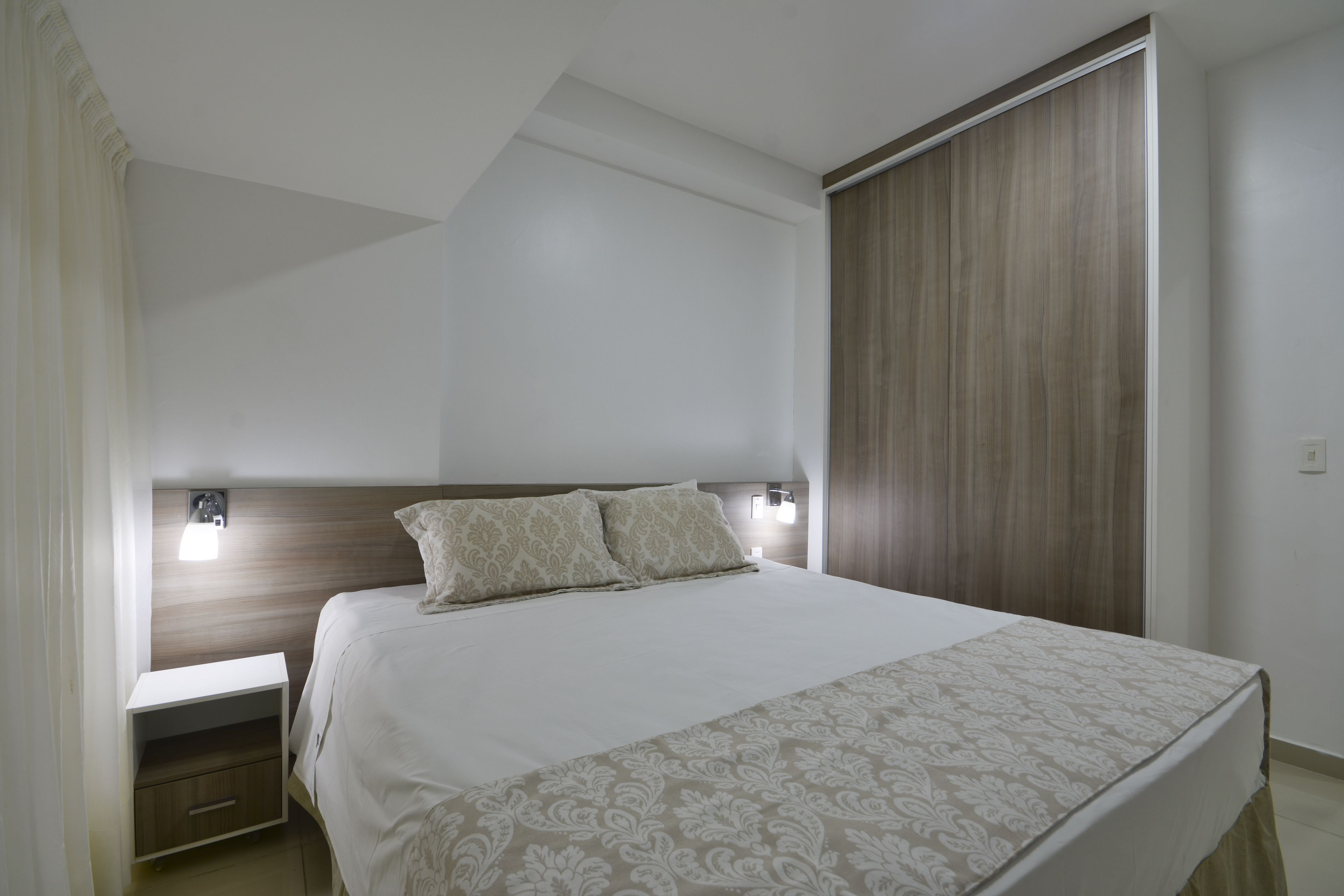 Une chambre à coucher avec un lit, des tables de chevet et une armoire.