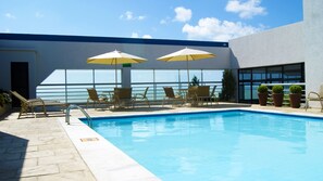 Una piscina al aire libre, sillones reclinables de piscina