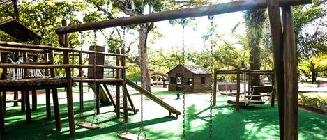 A playground with swings, a slide, and a wooden climbing structure.