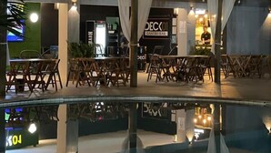 Un área junto a la piscina con sillones de descanso y una zona de bar con un letrero que dice "DECK GASTRO BAR".